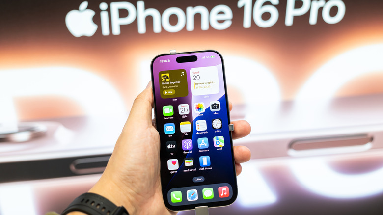 A hand holding the iPhone 16 Pro inside an Apple physical store.