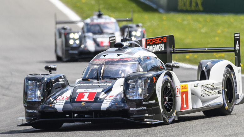 Two Porsche 919 race cars driving on a track with Michelin tires.