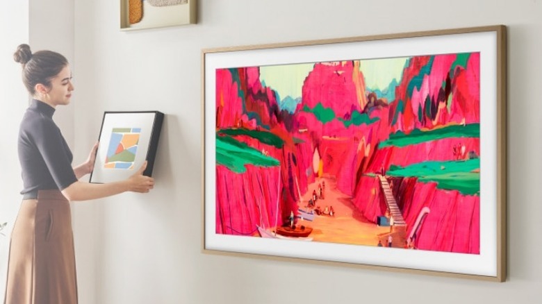 Woman hanging picture next to Samsung Frame TV