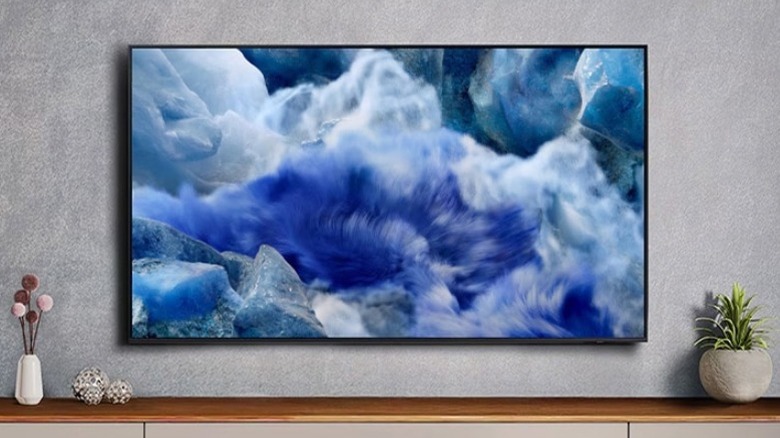 Samsung TV with blue wave illustration on screen mounted on concrete wall