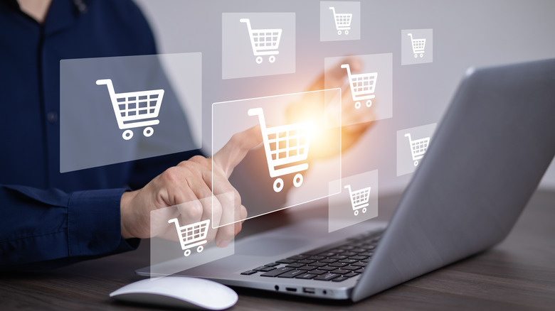 A person using a laptop to shop online, with illustrations of shopping carts floating above the laptop