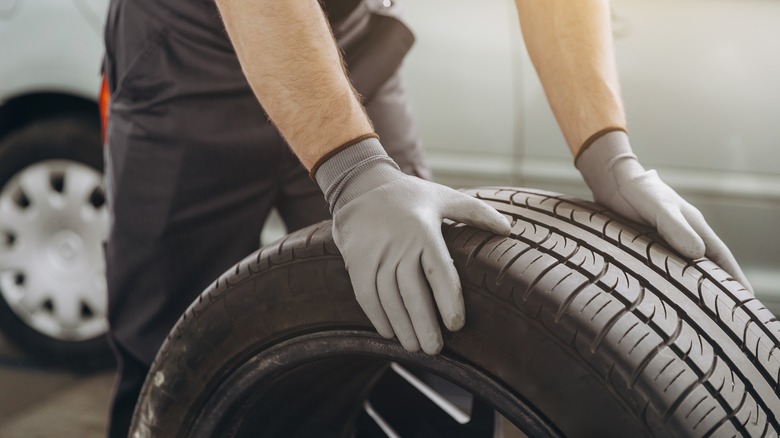 a mechanic rolling a replacement tire