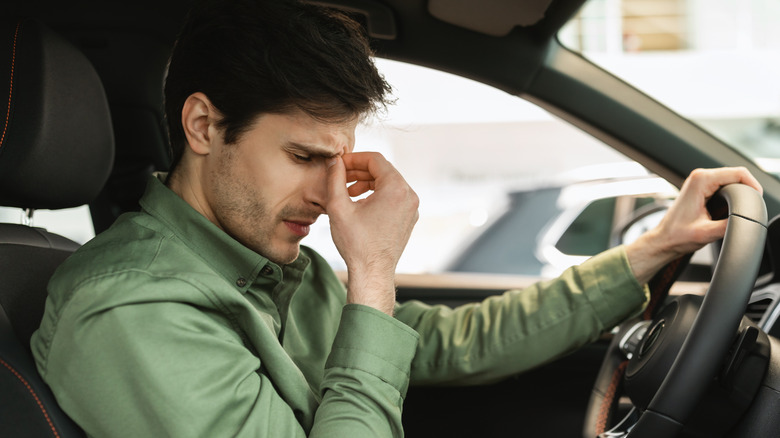 Driver looking disappointed behind a steering wheel