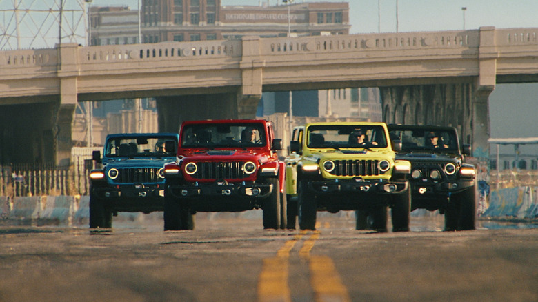 Blue, red, green, and black Jeep Wranglers driving on an urban road