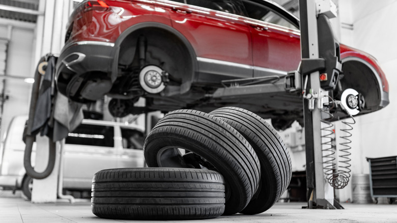 Car wheel service in auto repair garage with lifted vehicle and tires