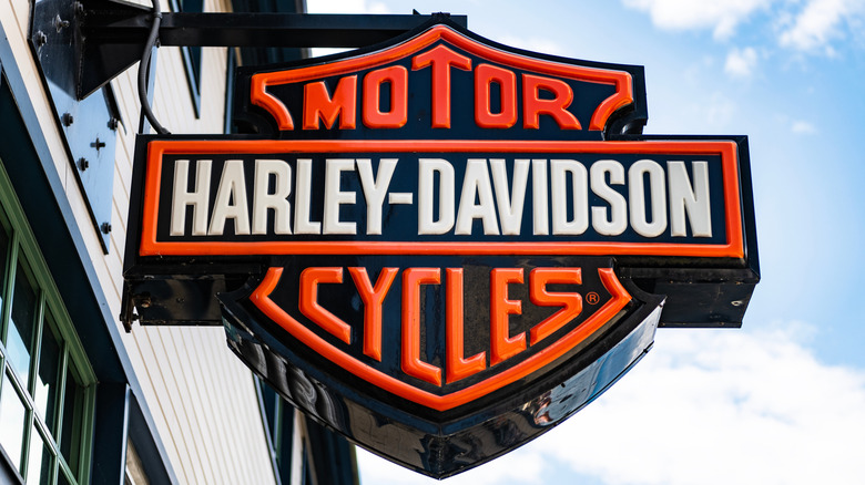 Harley Davidson signboard with brand logo hanging outside a dealership.