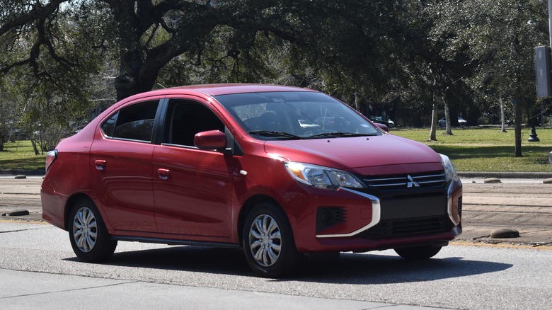 A red Mitsubishi Mirage G4 on the move on a road, front 3/4 view
