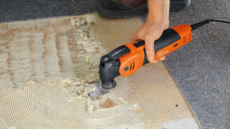 A Fein tool is used to peel a carpet off the floor