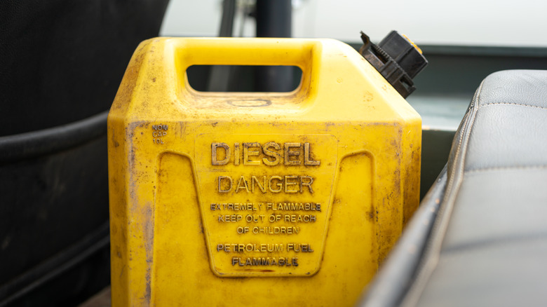 A dirty yellow diesel can placed in a car's rear passenger footwell.