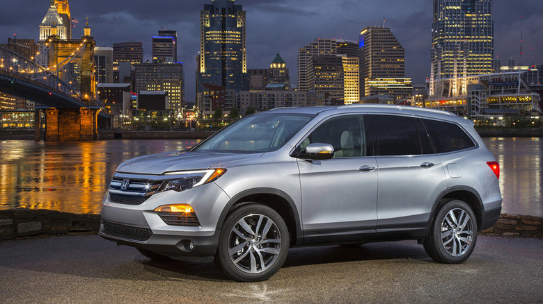 A 2016 silver Honda Pilot with a city skyline background