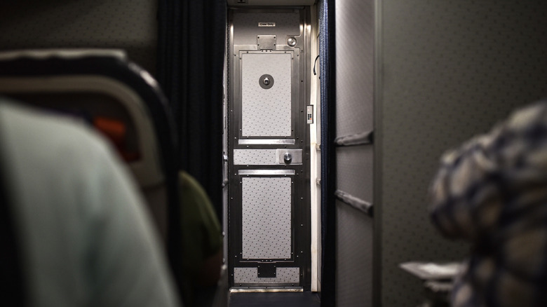 closed cockpit door on an airplane looking up the aisle