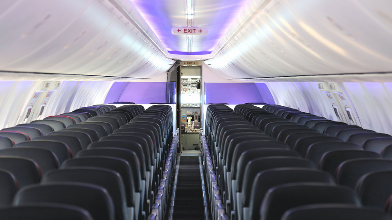 Inside a narrow commercial aircraft with the cockpit door open, showing the aircraft's flight deck