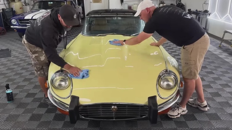 Jaguar E-Type being cleaned in garage.