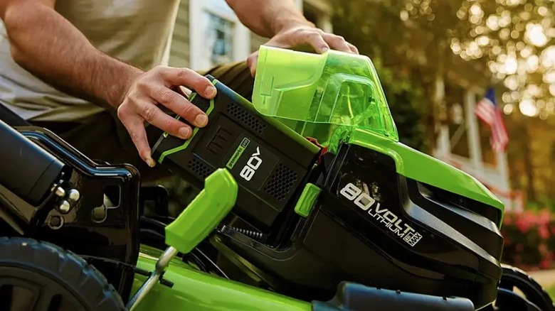 Person installing battery in Greenworks lawn mower