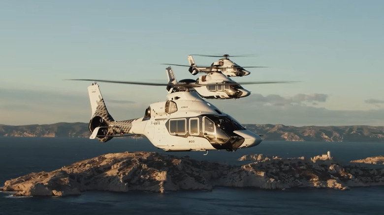 Three ACH160 helicopters in the air, with islands in the background.