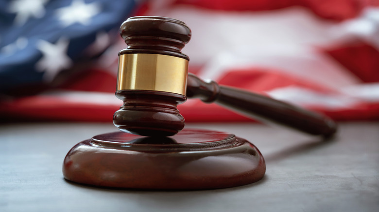 Close up of wooden judge gavel in front of an American flag