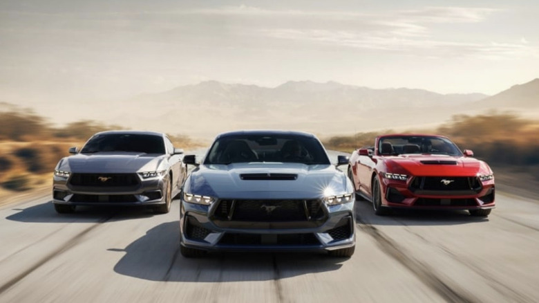 Three Ford Mustangs driving down the road