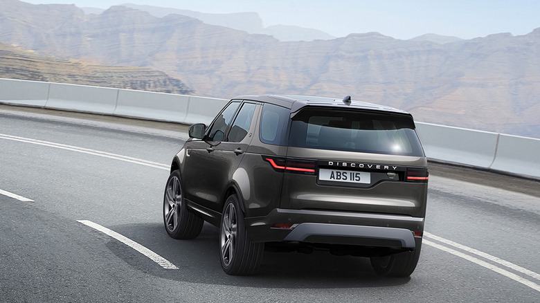 2023 Land Rover Discovery driving along mountain road, rear-left 3/4 view