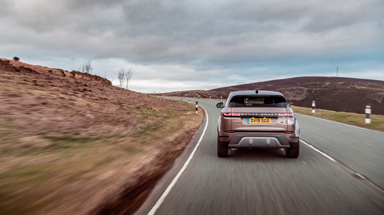 2020 Range Rover Evoque driving along arid road, rear-view