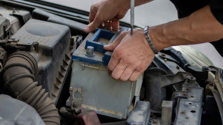 A person lifting a car battery.