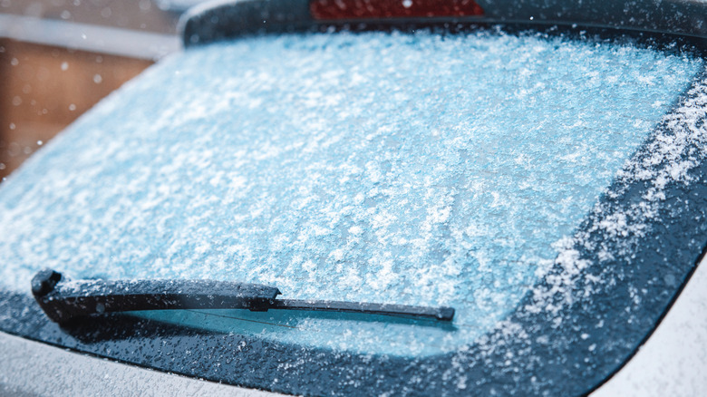 A snowy and icy rear window on an unidentified silver car