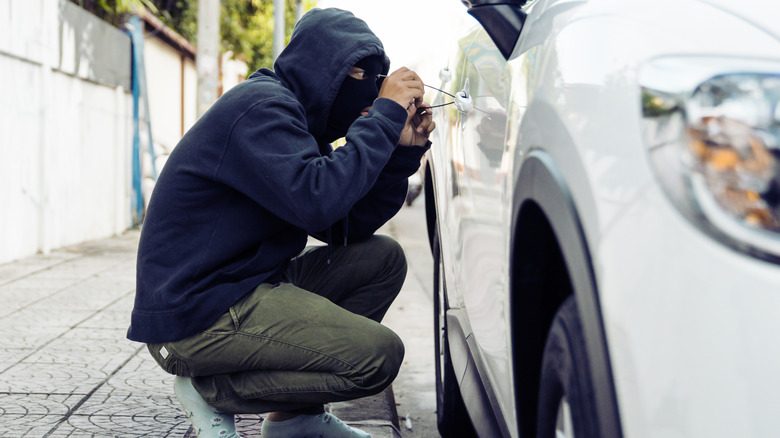 A thief trying to open a car's door