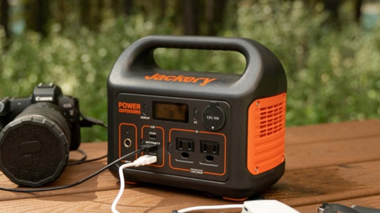 Jackery Explorer 300 plugged into camera on picnic table