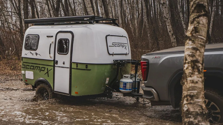Pickup truck towing a Scamp X trailer through mud