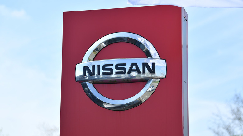 Chrome Nissan logo on red dealership sign