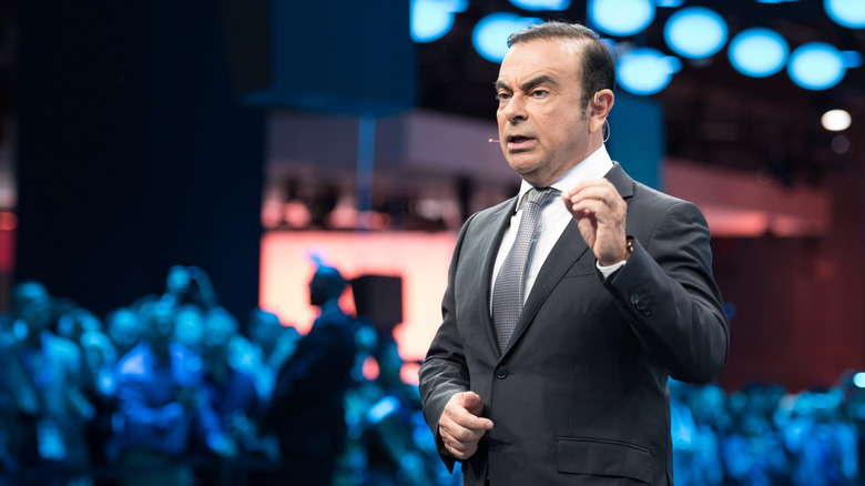 Carlos Ghosn speaking at conference, standing with crowd in the background