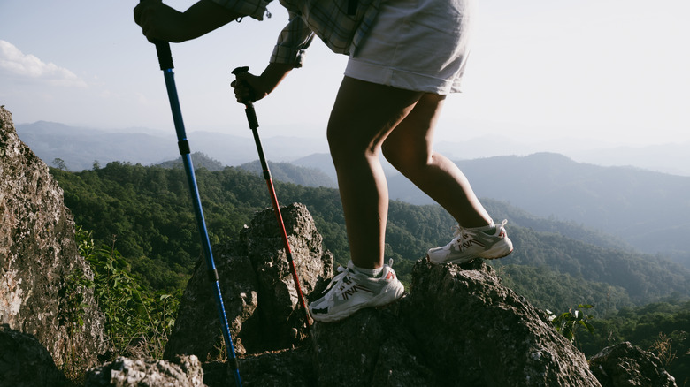 Person walking over mountain rocks holding trekking poles