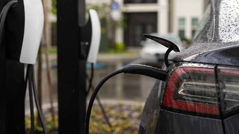 Electric vehicle plugged in at charging station.