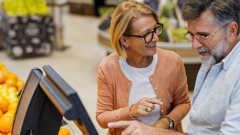 elderly couple uses self-checkout