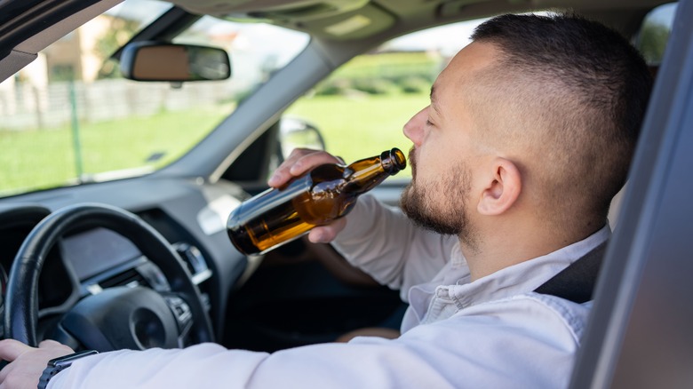 Man drinking alcohol while driving a car