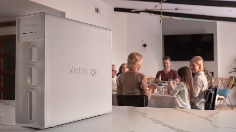 Waterdrop X12 on countertop with family eating dinner in the background