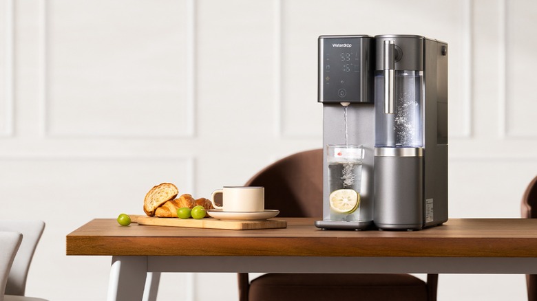 Waterdrop A2 on tabletop with tray of food and a mug next to it