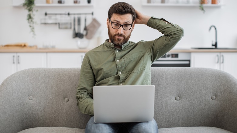 Man sitting in his living room looking at laptop
