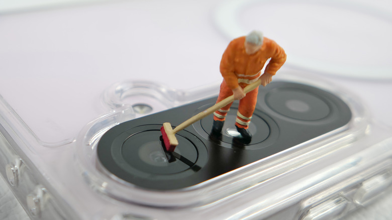 Miniature model of janitor cleaning lenses of a phone camera