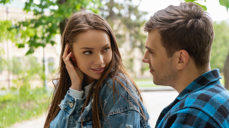 woman touching hair while looking at a man