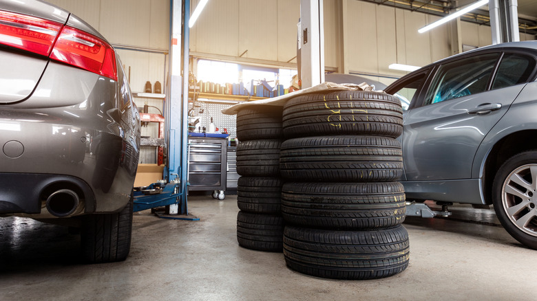 Tires stacked on the floor in a car repair shop.