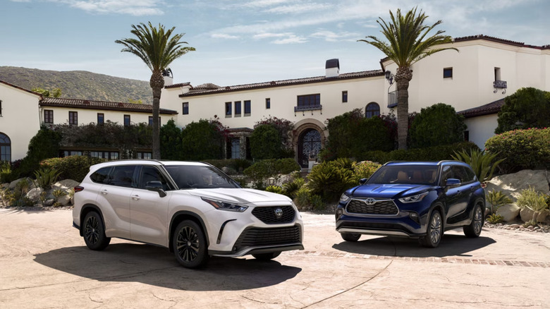 head-on view of  blue and white Toyota Highlanders parked in driveway of Spanish-style home