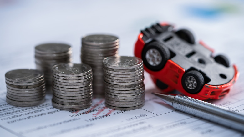A small car beside a stack of coins.
