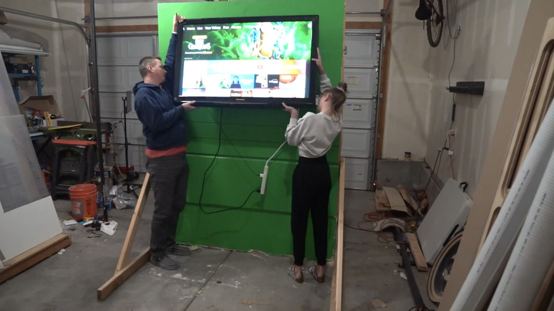 Two person attempting TV mounting on a wood wall