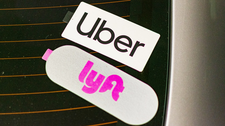 Uber and Lyft emblem on stickers on dusty rear window advertise a vehicle offering shared rides