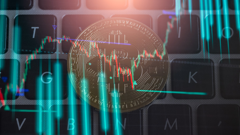 A Bitcoin on a keyboard with a stock market graph overlaid on top