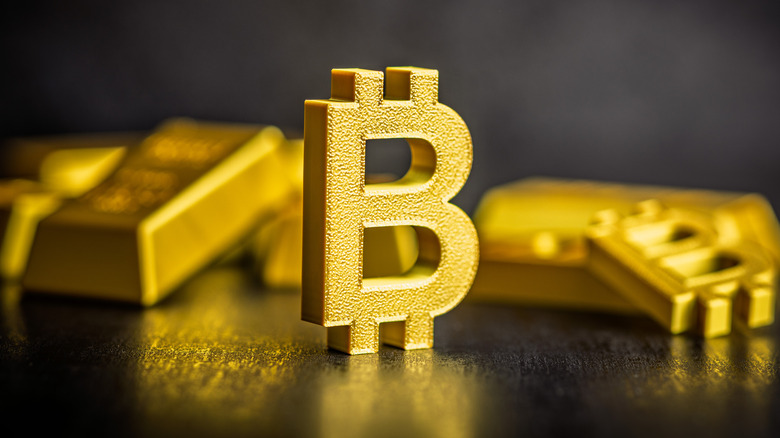 Bitcoin logo and gold bars on a table