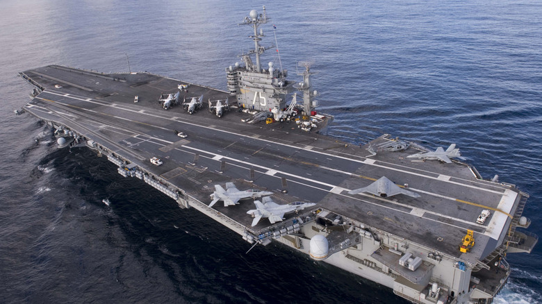 Aircraft carrier in calm water with several planes on deck