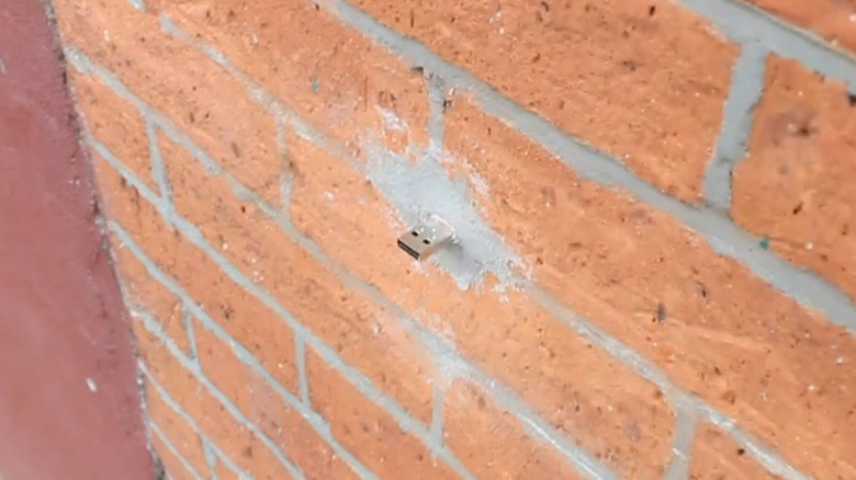 A USB A drive sticking out of a brick wall.