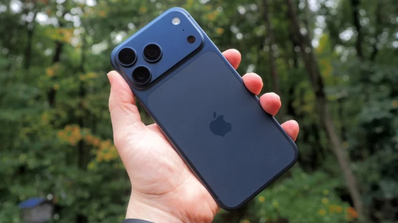 Holding iPhone 17 Pro Max in front of wooded area
