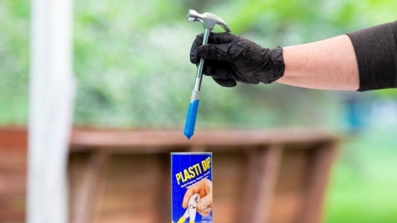 Person dipping hammer handle in blue Plasti-Dip